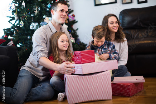 Large cheerful family handing gifts during Christmas at home