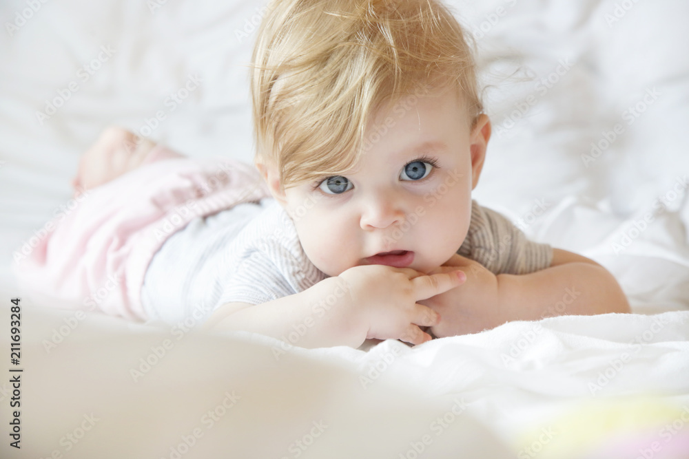 Portrait of adorable blonde baby girl laying on the bed Portrait of adorable blonde baby girl laying on the bed
