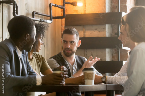 Fotografie Multiracial friends sitting in cafe enjoying coffee during work break, listening
