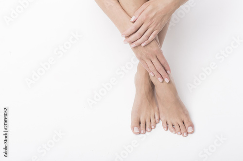 Beautiful legs and hands on white background. Pedicure and manicure time.
