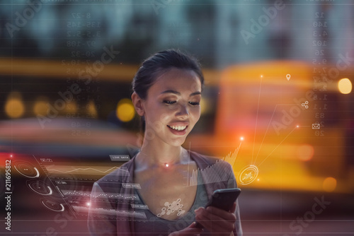 Staying up to date with technology in a fast moving world, concept. A young asian woman is using an innovative future technology to view her phone data and functions in holographic display around her photo
