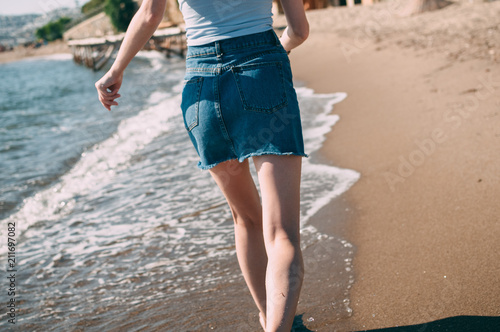 Young girl runs along the sea sandy beach barefoot, concept, legs.