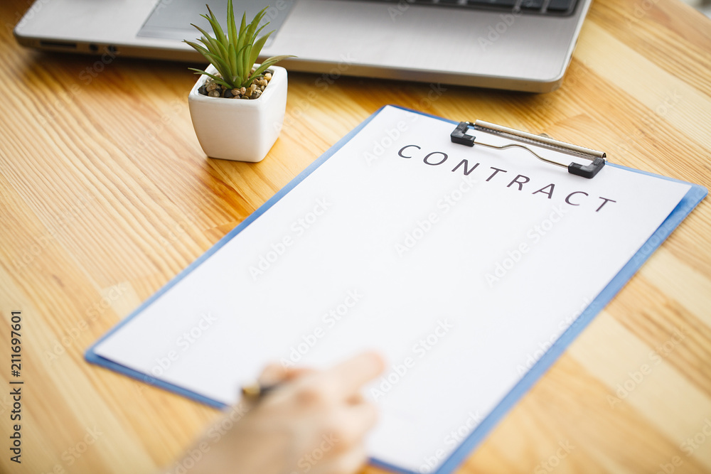 Business woman sitting at office desk signing a contract with shallow focus on signature. Business woman sitting at office desk signing a contract with shallow focus on signature.