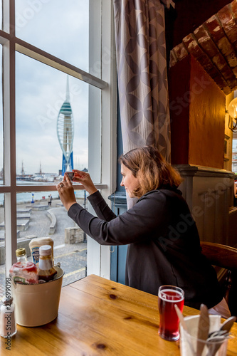 Woman in Portsmouth pub near the window at sunset, UK