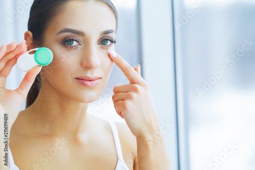 Health and Medicine. A Beautiful Young Woman With A Smile Holds A Contact Lens Container. Eye Care. Healthy Vision. Girl with Green Eyes. High Resolution