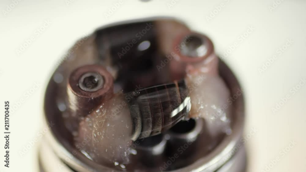 Rebuildable dripping atomizer or RDA for vaping or e-cigarette coil and cotton stripes wetted with e-liquid, modern vape device for quit smoking, macro photo with selective focus 4K Rebuildable dripping atomizer or RDA for vaping or e-cigarette coil and cotton stripes wetted with e-liquid, modern vape device for quit smoking, macro photo with selective focus 4K