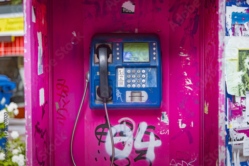 Old magenta phone booth sprayed with graffiti in Thessaloniki, Greece, unused for a long time