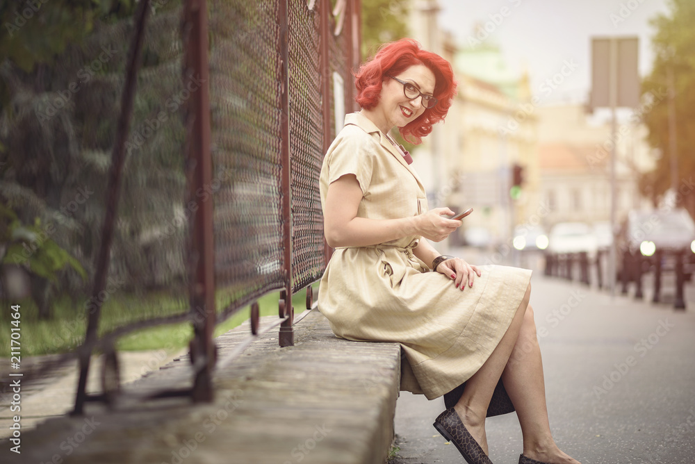 Young fashionable woman dressed in retro clothes using her cell phone, enjoying a beautiful day in the city Young fashionable woman dressed in retro clothes using her cell phone, enjoying a beautiful day in the city