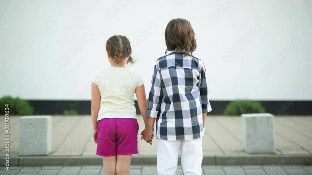 A Couple of Children Stand Back and Hold on to Their Hands. The Wind Waves Their Blond Hair. A Couple of Children Stand Back and Hold on to Their Hands. The Wind Waves Their Blond Hair.