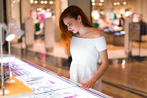 Young redhead pretty girl in a shopping center looking at jewelry photo