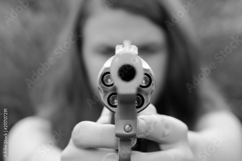 A girl aiming a stainless steel revolver loaded with hollow point bullets shot in black and white