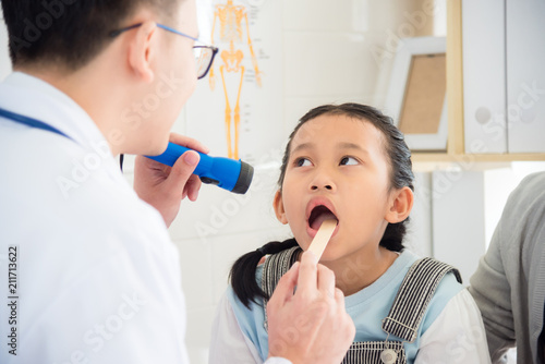 Young asian girl open her mouth for doctor doing oral examination.