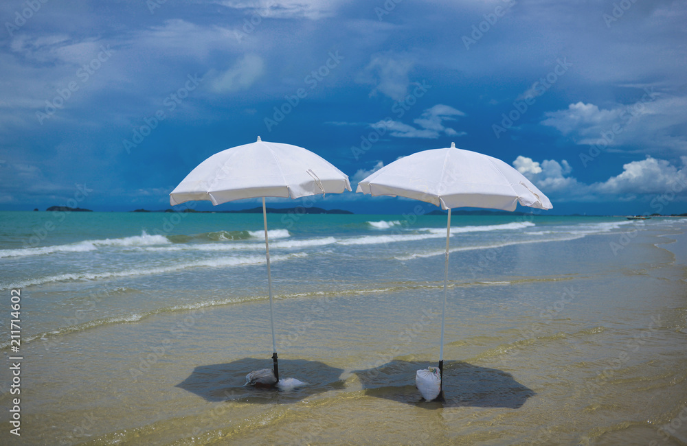 Two white umbrella on the beach at a sunny day.