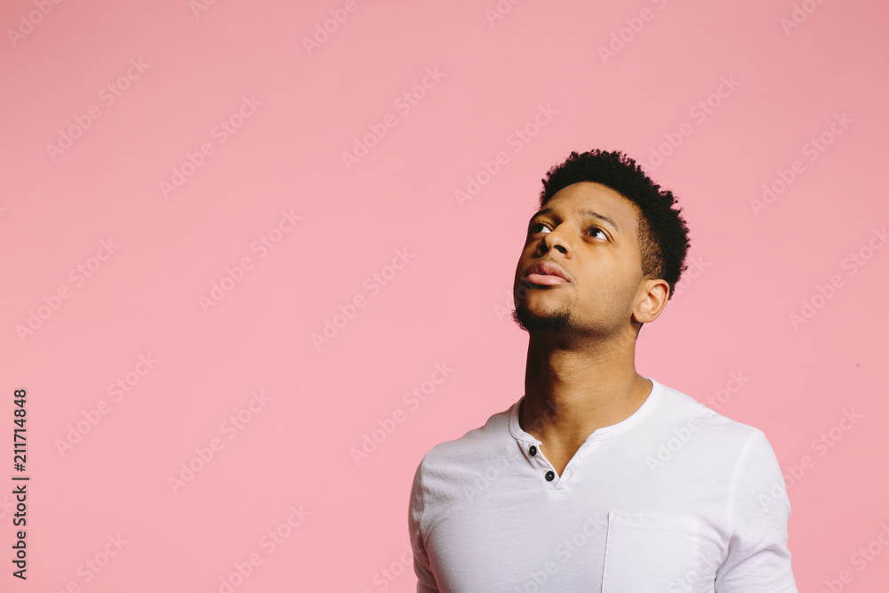 Close up portrait of a young man looking up and left with interest, ,  isolated on pink studio background Stock Photo | Adobe Stock