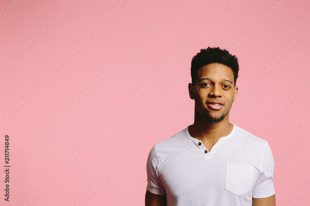 Young man looking at camera with interest, isolated on pink studio background Young man looking at camera with interest, isolated on pink studio background