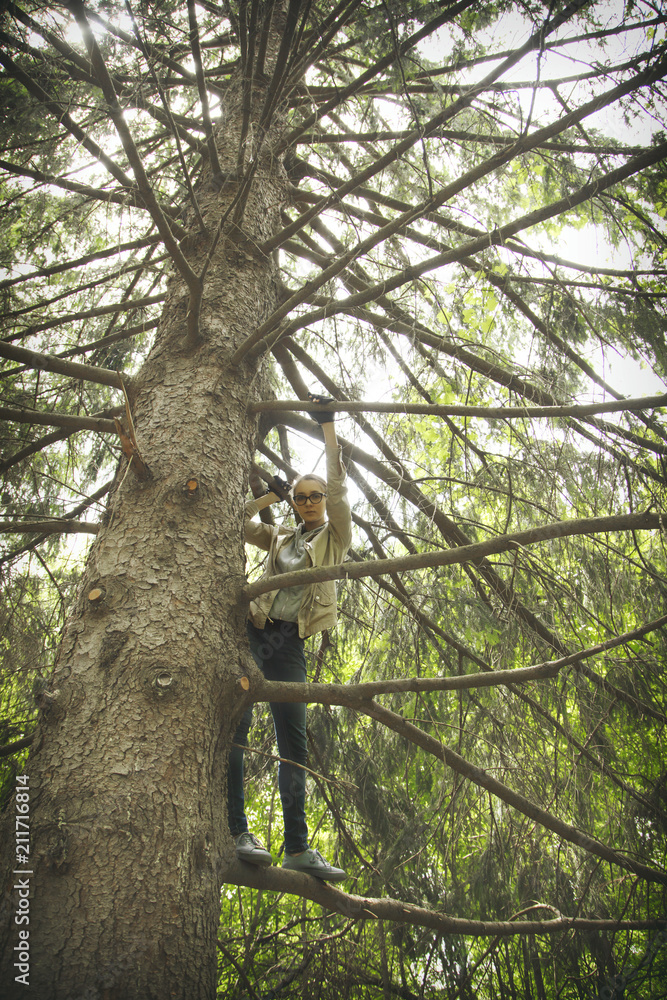 Fototapeta premium Pretty girl standing on a branch tree