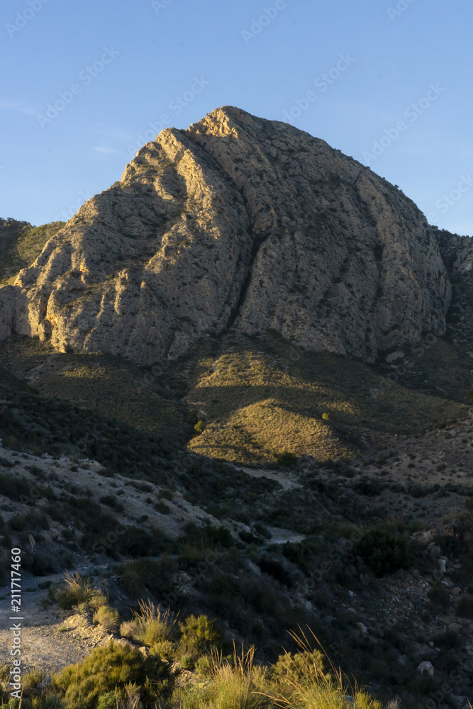 Mountain pico del agudo  La Murada Orihuela, Spain Mountain landscape with path. Hiking and healthy life.natural landscape of the Spanish Levante with vgetation and arid land sunrise light in spring