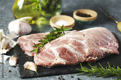Raw pork meat for grill with ingredients for cooking, dark background.