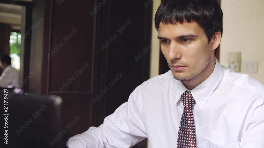 Handsome serious businessman working on an office. Young man typing on a laptop. 3840x2160 Handsome serious businessman working on an office. Young man typing on a laptop. 3840x2160
