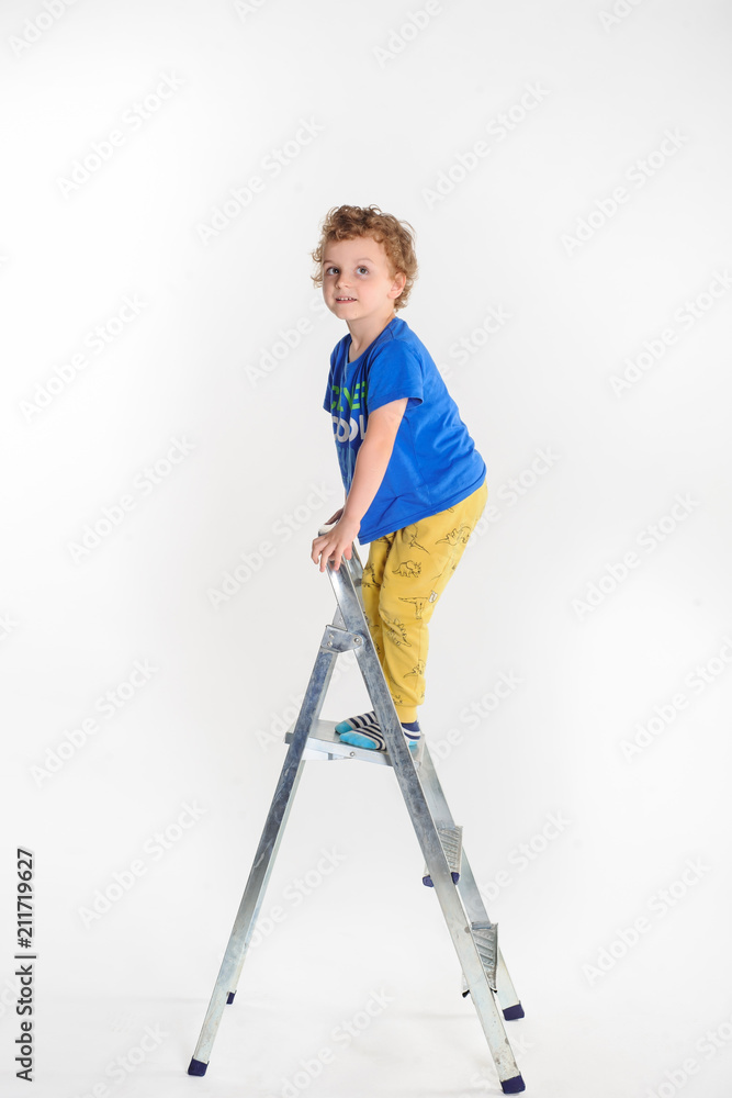 Handsome boy with long curly hair standing on the stepladder Handsome boy with long curly hair standing on the stepladder