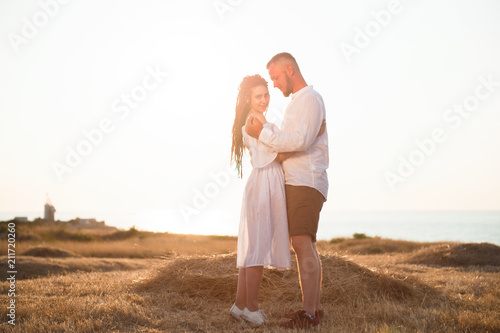 happy smiling young newly married couple outdoors summer field and sea