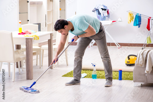 Young attractive man husband doing mopping at home