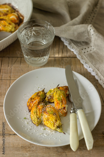 Stuffed with ricotta and cheese baked zucchini and pumpkin flowers served with a glass of mineral water. Rutik style. photo