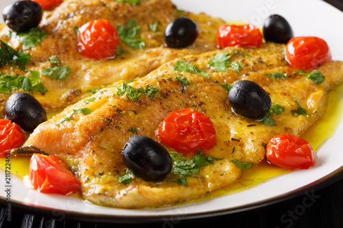 Fried trout fillets with garlic butter sauce, tomatoes and olives closeup. horizontal