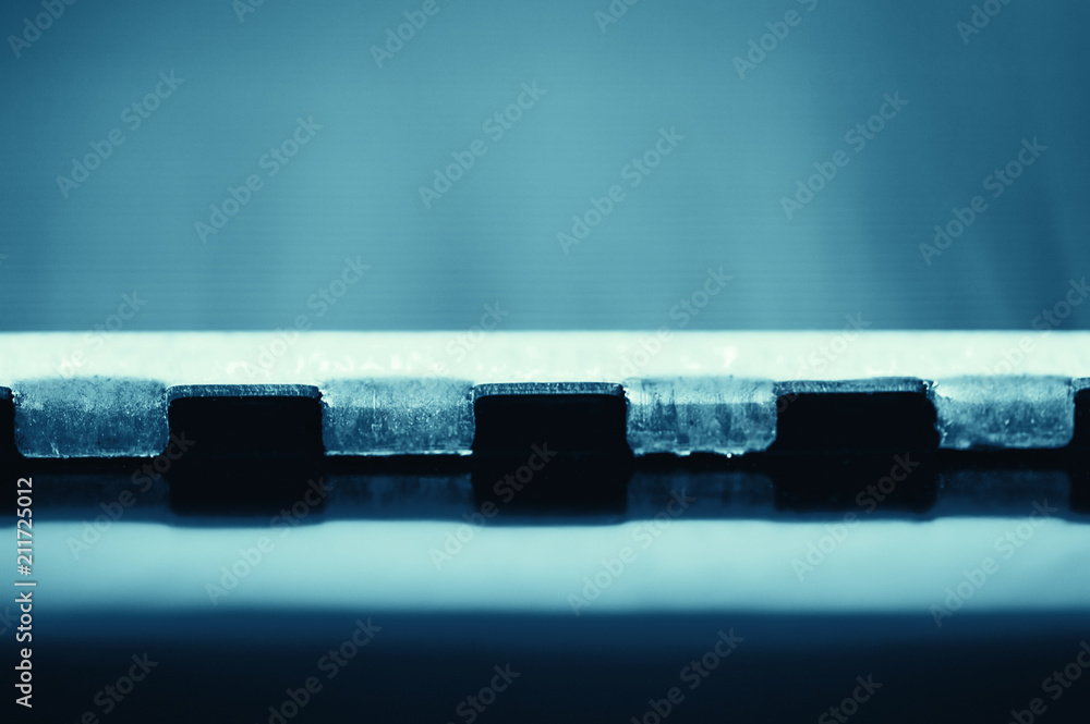 Naklejka premium Detailed background of fragment of automotive radiator in macro with copy space. Monochrome image of metallic auto part is close-up. Empty surface of steel texture in blue tone.