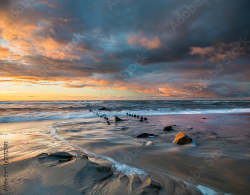 sunset over the sea beach in Poland, waves dynamically breaking into the beach