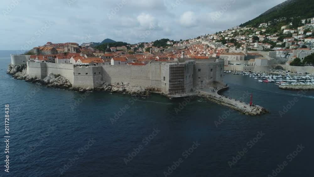 Flying over defense walls revealing beautiful city of Dubrovnik, a popular tourist destination and historic place on the Croatian coast Flying over defense walls revealing beautiful city of Dubrovnik, a popular tourist destination and historic place on the Croatian coast