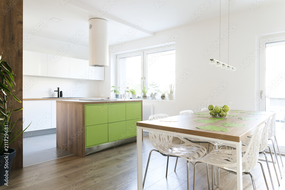Modern and design scandinavian kitchen with plants, kitchen table and accessories . Sunny and bright space with white wall. Modern and design scandinavian kitchen with plants, kitchen table and accessories . Sunny and bright space with white wall.
