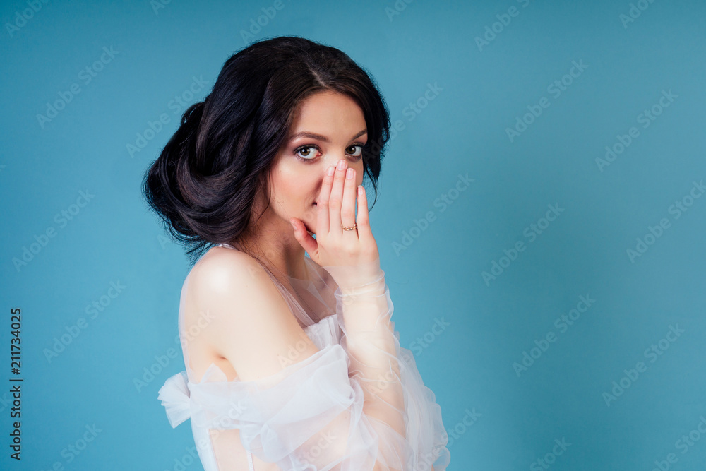 Indian woman in a wedding dress ieavesdrops and gossips on a blue background in the studio Indian woman in a wedding dress ieavesdrops and gossips on a blue background in the studio