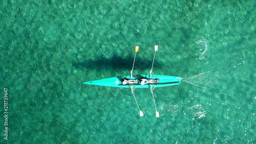 Aerial drone bird's eye view of kayak cruising in tropical seascape with turquoise and sapphire clear waters