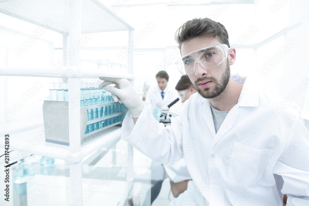 Young male scientist looking at a sample in a test tube side vie Young male scientist looking at a sample in a test tube side vie