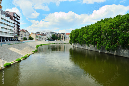 Rzeka płynąca przez miasto, mosty i drzewa nad brzegiem.