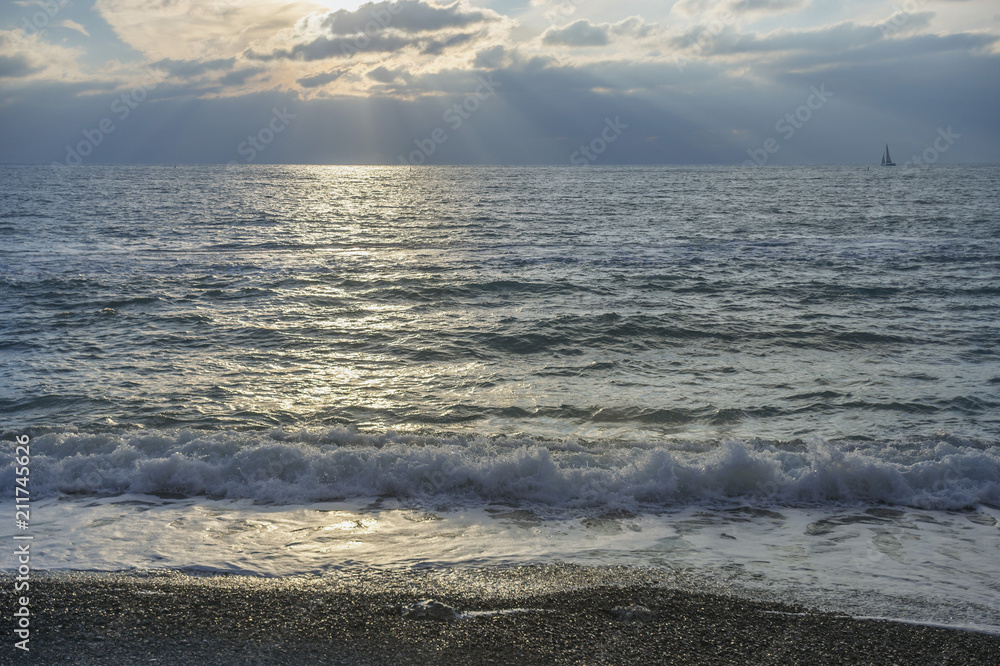 Obraz premium fragment of the stony beach of the beach with a mobile sea wave against a beautiful sunset