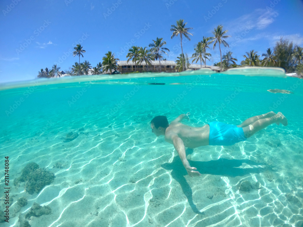HALF UNDERWATER Active young man swims along the breathtaking exotic sandy shore HALF UNDERWATER Active young man swims along the breathtaking exotic sandy shore