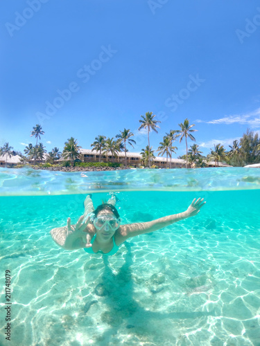 HALF UNDERWATER: Woman snorkeling away from oceanfront resort gives the ok sign.