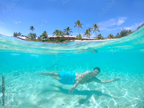 HALF UNDERWATER: Active man on holiday diving near the sunny tropical island.
