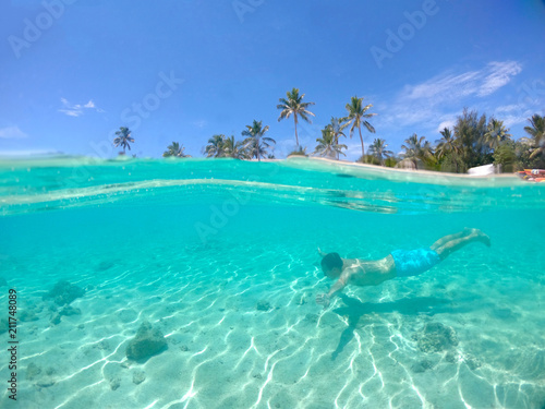 HALF UNDERWATER: Young male tourist swims near the awesome paradise island.