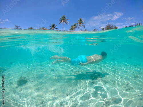 HALF UNDERWATER: Fit young man dives in the beautiful ocean near tropical island