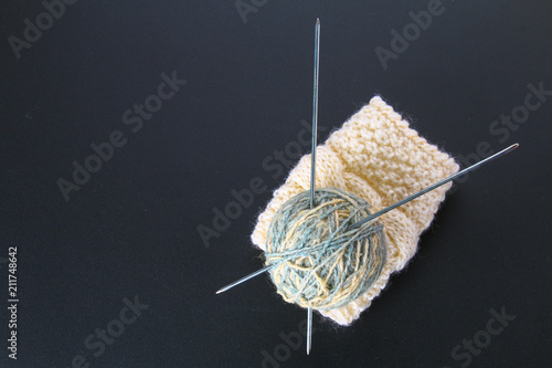A ball of wool with knitting needles and socks on a gray table. Needlework. photo