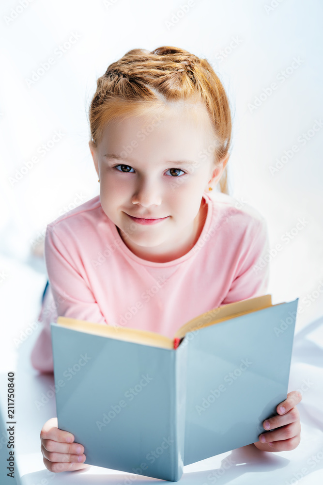 adorable child holding book and smiling at camera adorable child holding book and smiling at camera