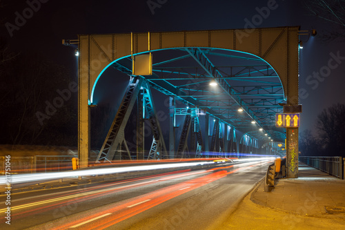 Moving car with blur light through Pilsudski Bridge at night in Torun. Poland. Europe.