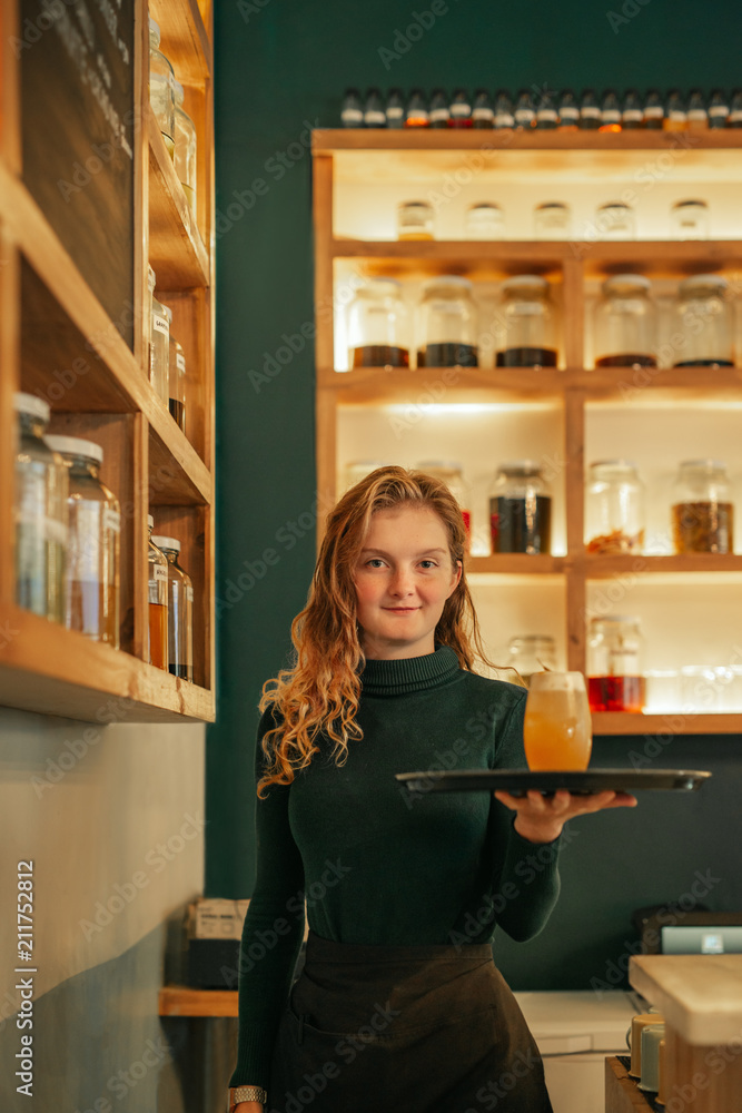 Smiling young waitress serving drinks in a trendy bar