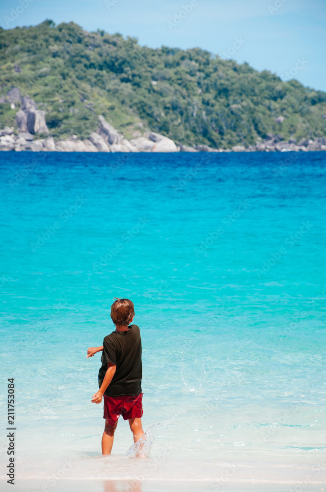 European kid on Similan island white sand beach and vibrant turqouise blue Andaman sea. Phang Nga - Phuket, Thailand European kid on Similan island white sand beach and vibrant turqouise blue Andaman sea. Phang Nga - Phuket, Thailand