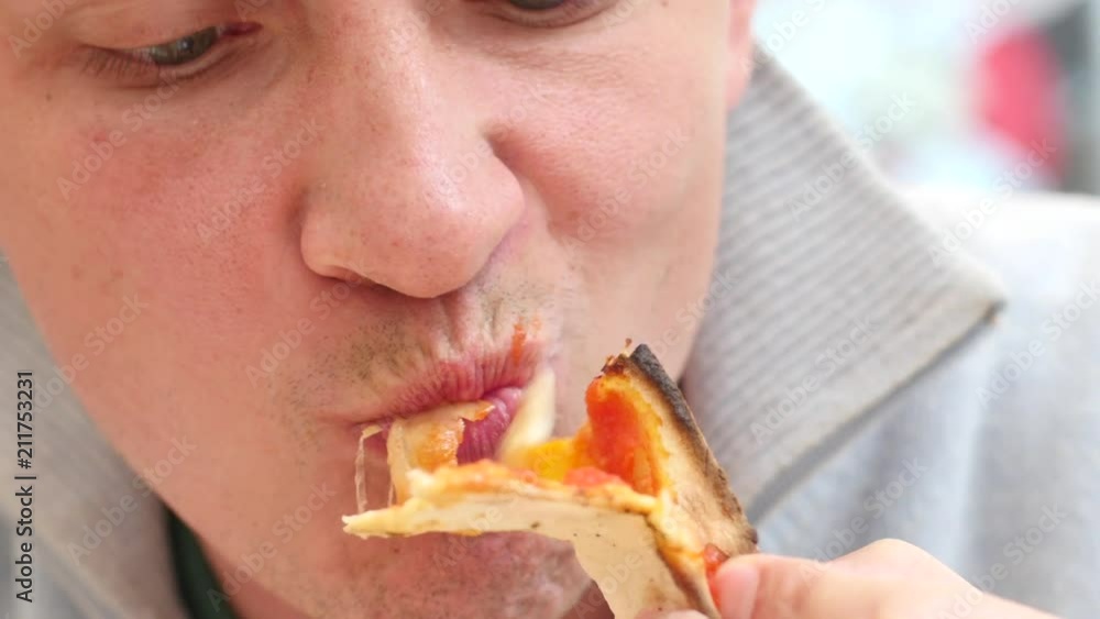 Young man guy eating chewing a piece of pizza in Rome street restaurant in Italy Young man guy eating chewing a piece of pizza in Rome street restaurant in Italy