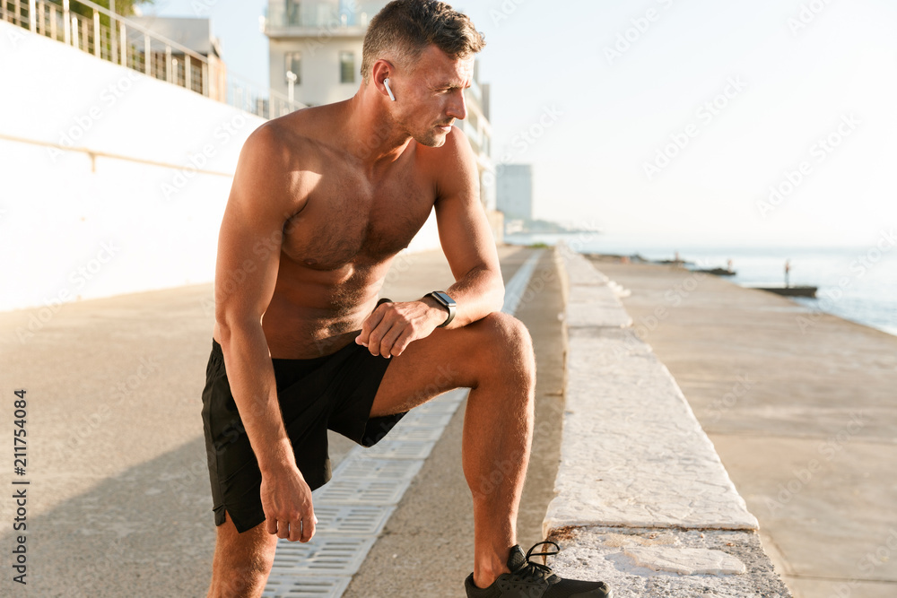 Obraz premium Confident handsome shirtless sportsman with earphones