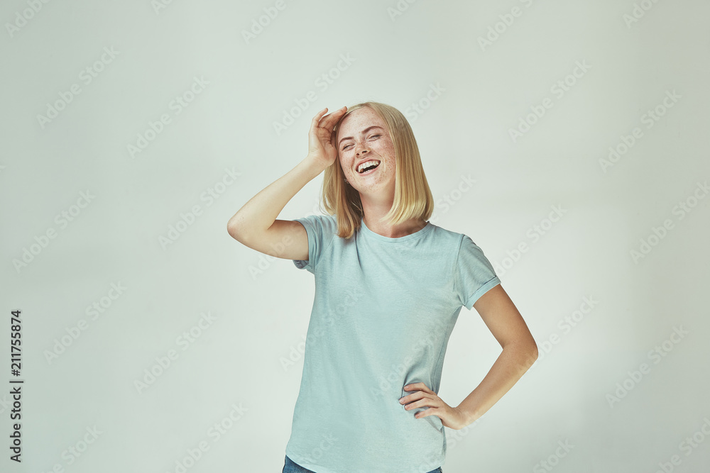 The happy freckled woman standing and smiling against gray background. The happy freckled woman standing and smiling against gray background.